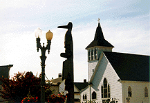 photo of lightpost, totem pole, and church